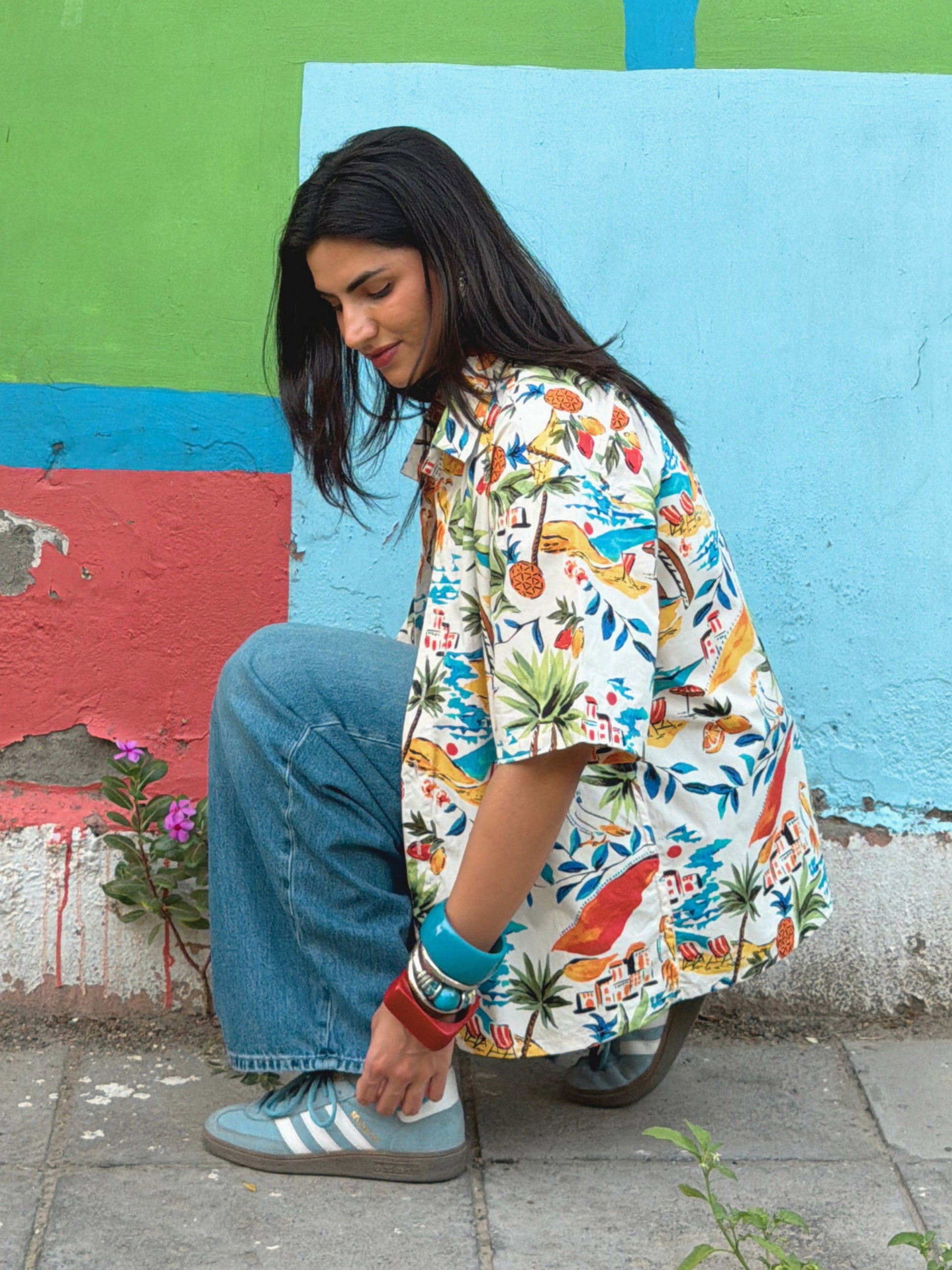 model wearing the printed ikami mykonos shirt against a multi coloured wall