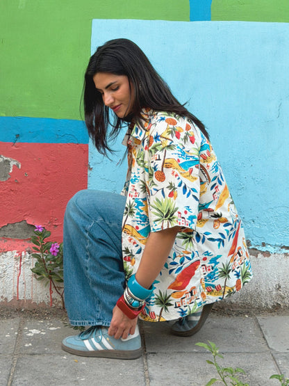 model wearing the printed ikami mykonos shirt against a multi coloured wall