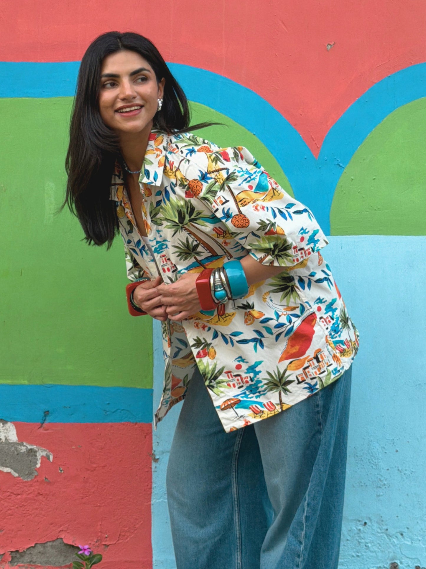 model wearing the colourful ikami mykonos shirt against a multi coloured wall