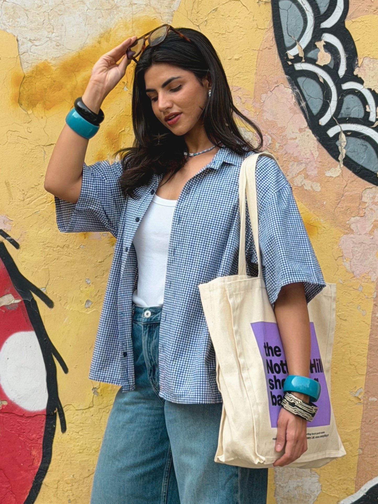 Woman wearing the cool ikami london shirt against a graffiti-covered wall.