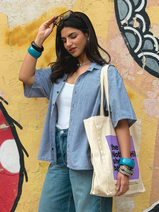 Woman wearing the cool ikami london shirt against a graffiti-covered wall.